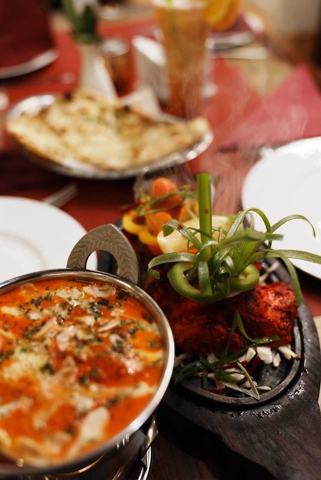 Cremiges Curry im Karahi, Tandoori-Hähnchen auf der heißen Platte und Naan-Brot