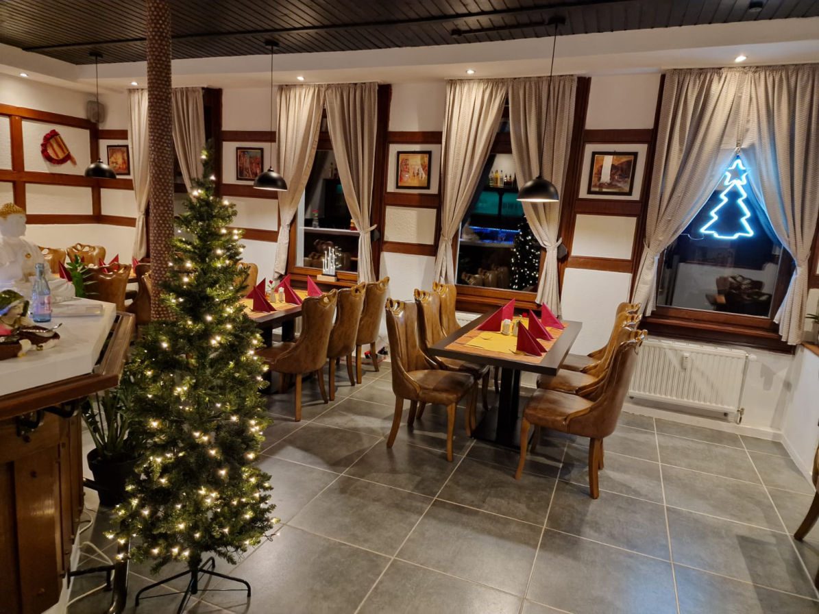 Gastraum mit geschmücktem Tannenbaum und gedeckten Tischen