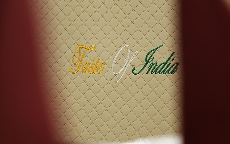 Speisekarte von Taste of India mit eingesticktem Schriftzug auf dem Tisch