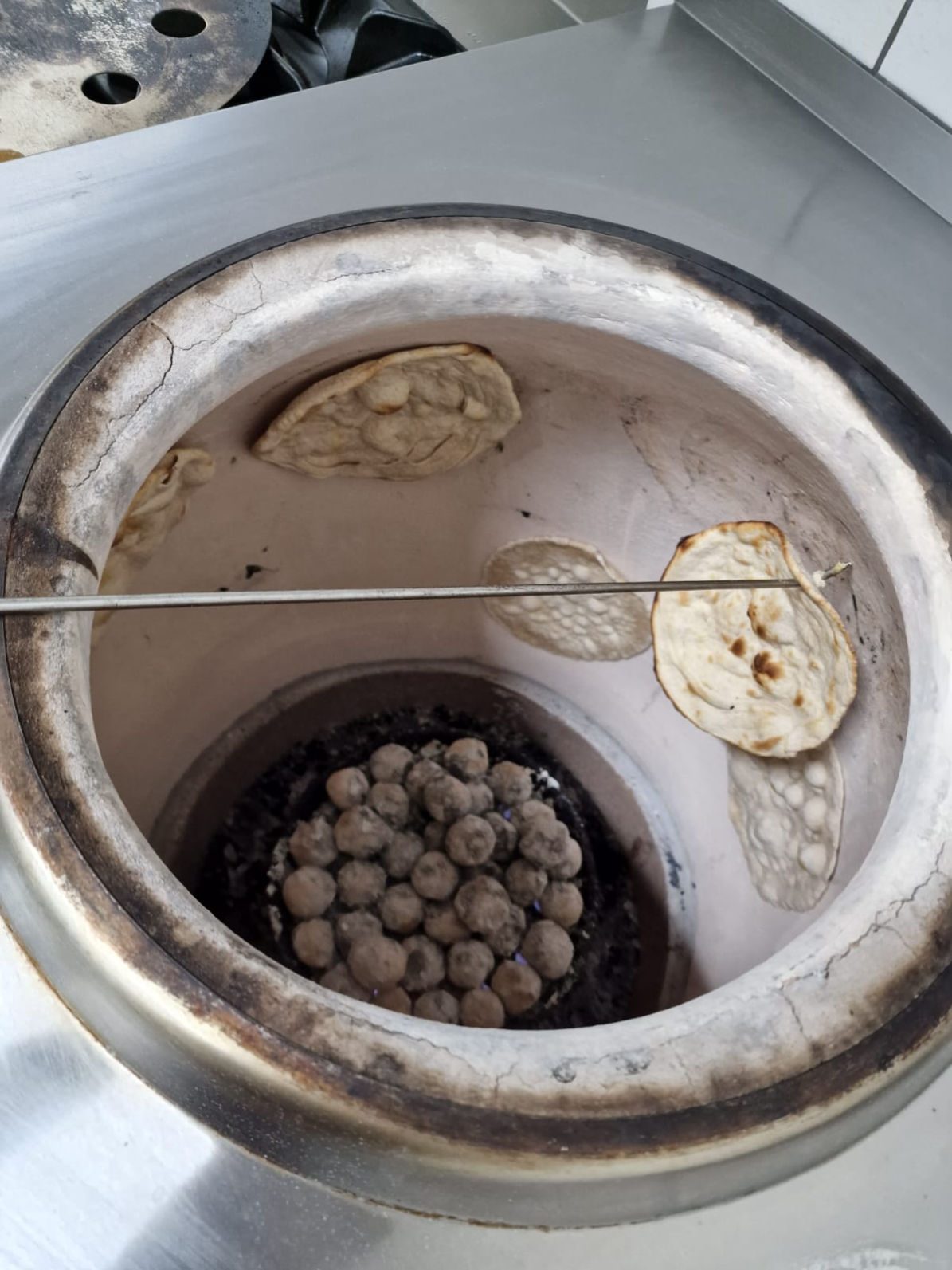 Blick in den glühenden Tandoor mit backendem Naan